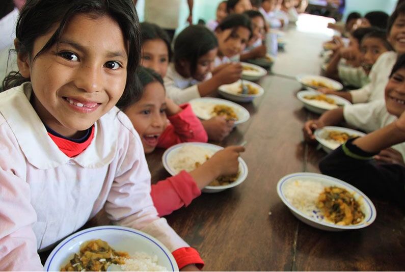 Children smiling and enjoying a meal together.