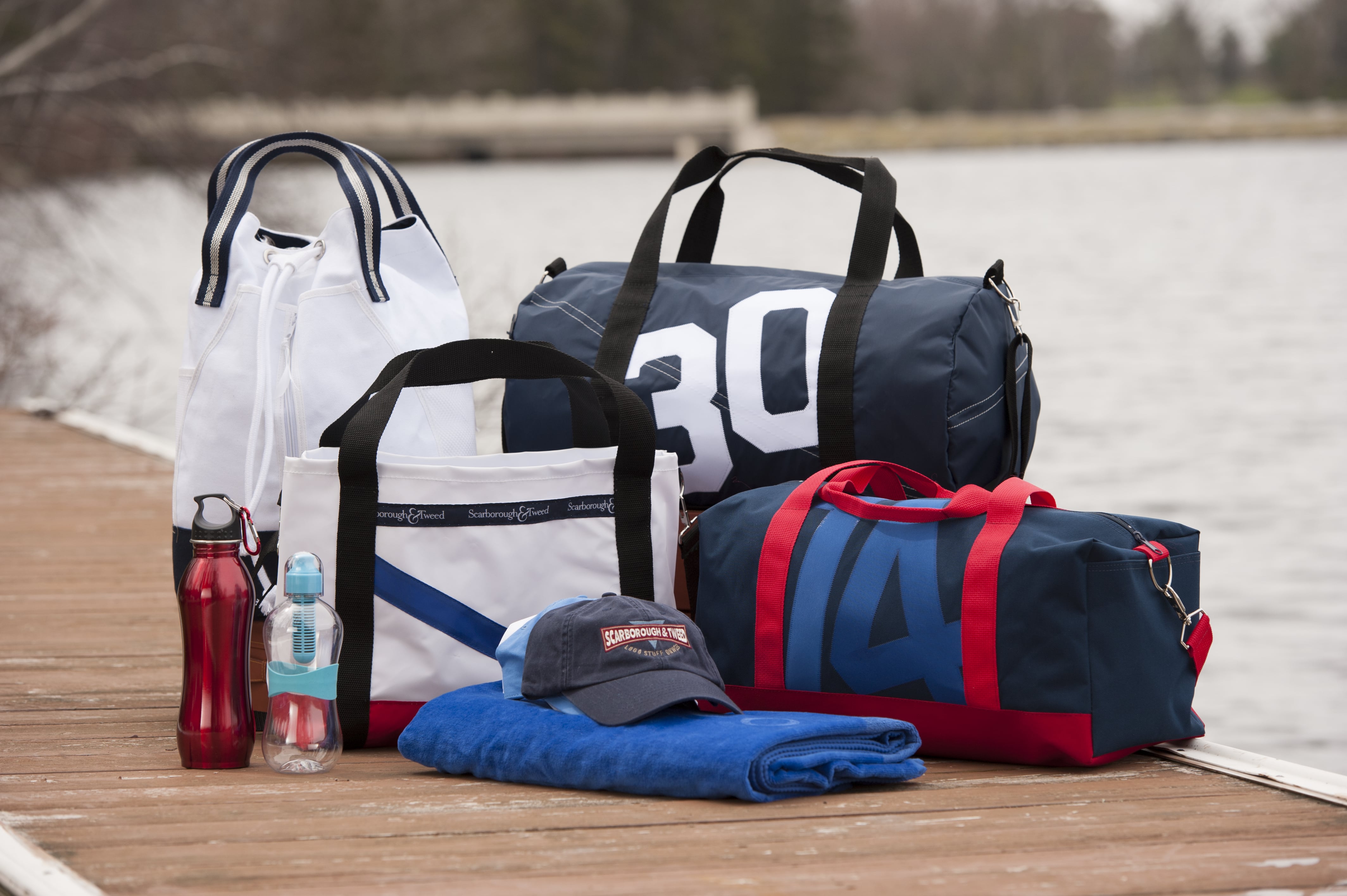 Various bags, water bottle, towel, and cap on a dock.