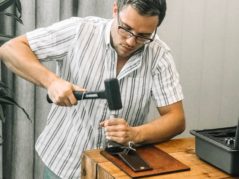 Person using a hammer to assemble a leather item
